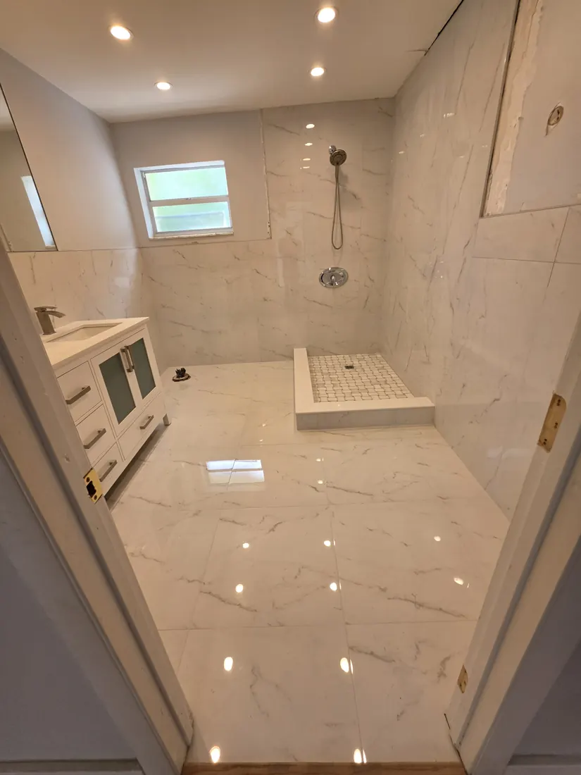 Modern bathroom renovation in Hollywood with marble-look tile, a white vanity and tiled shower